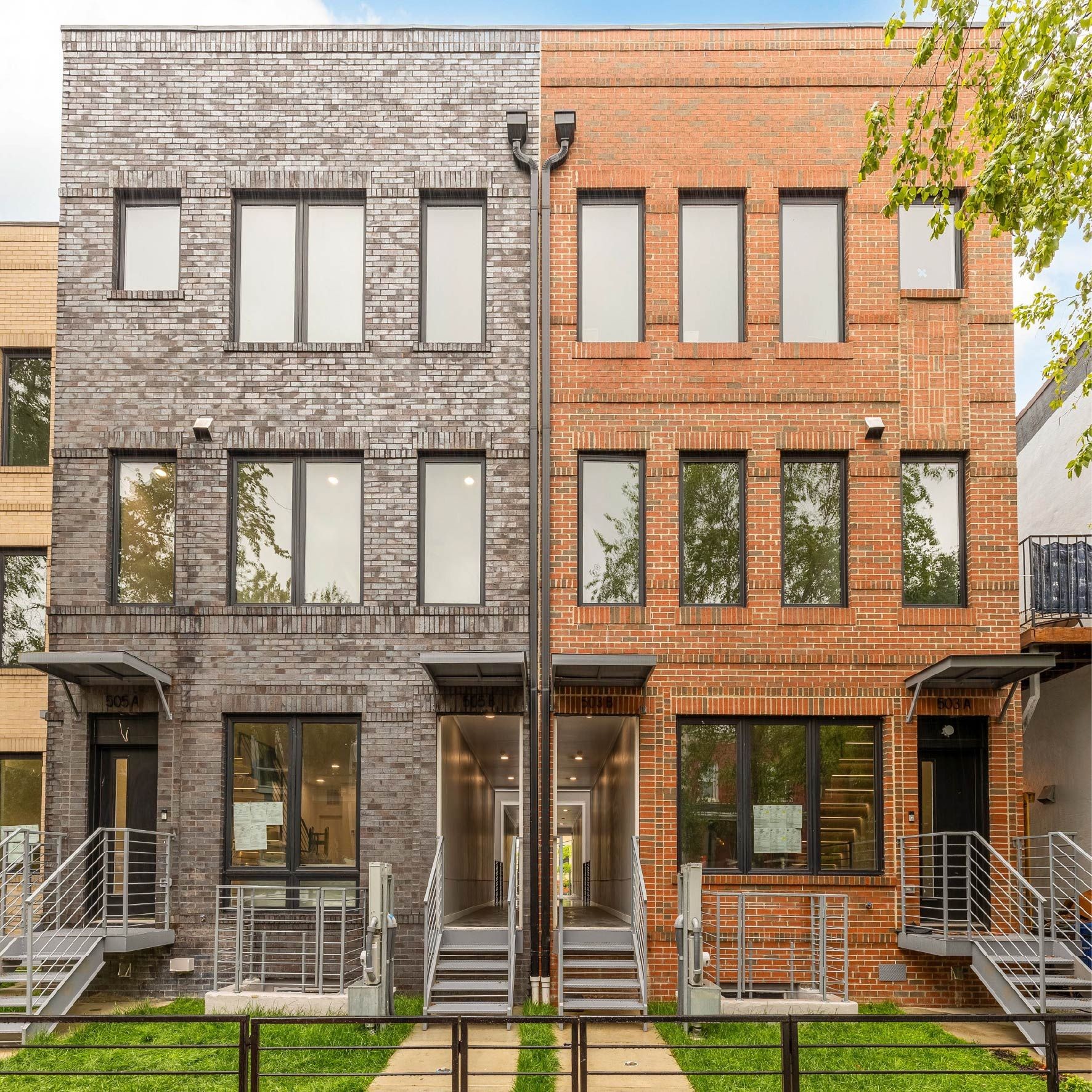 Two adjacent modern brick buildings with large windows and front metal staircases.